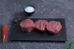 Three fresh beef tenderloin steaks on a slate board with chilli and sea salt - The Meat Master Butchery