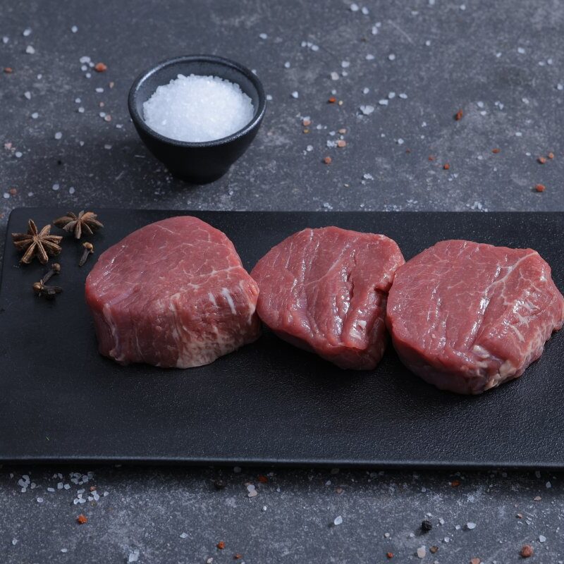 Three fresh beef tenderloin steaks on a slate board with chilli and sea salt - The Meat Master Butchery