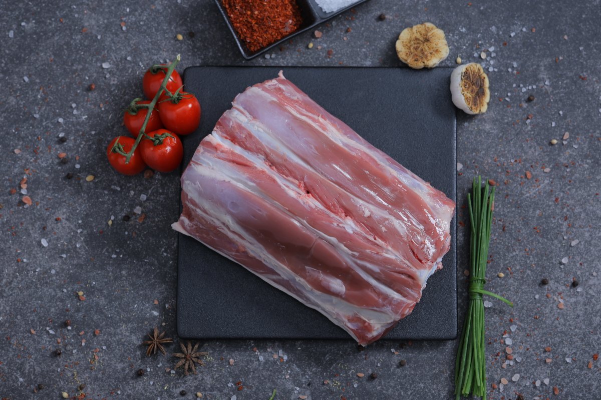 Fresh raw lamb ribs rack on a slate board with cherry tomatoes and spices - The Meat Master Butchery
