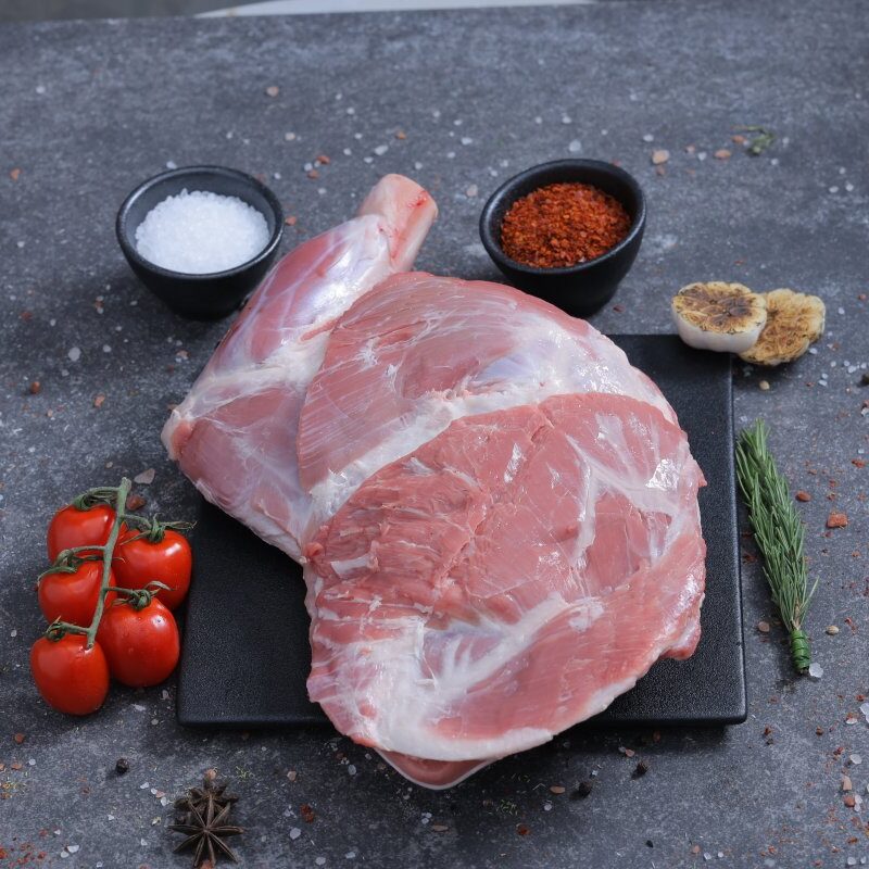 Whole raw lamb shoulder joint on a slate board with sea salt and spices - The Meat Master Butchery