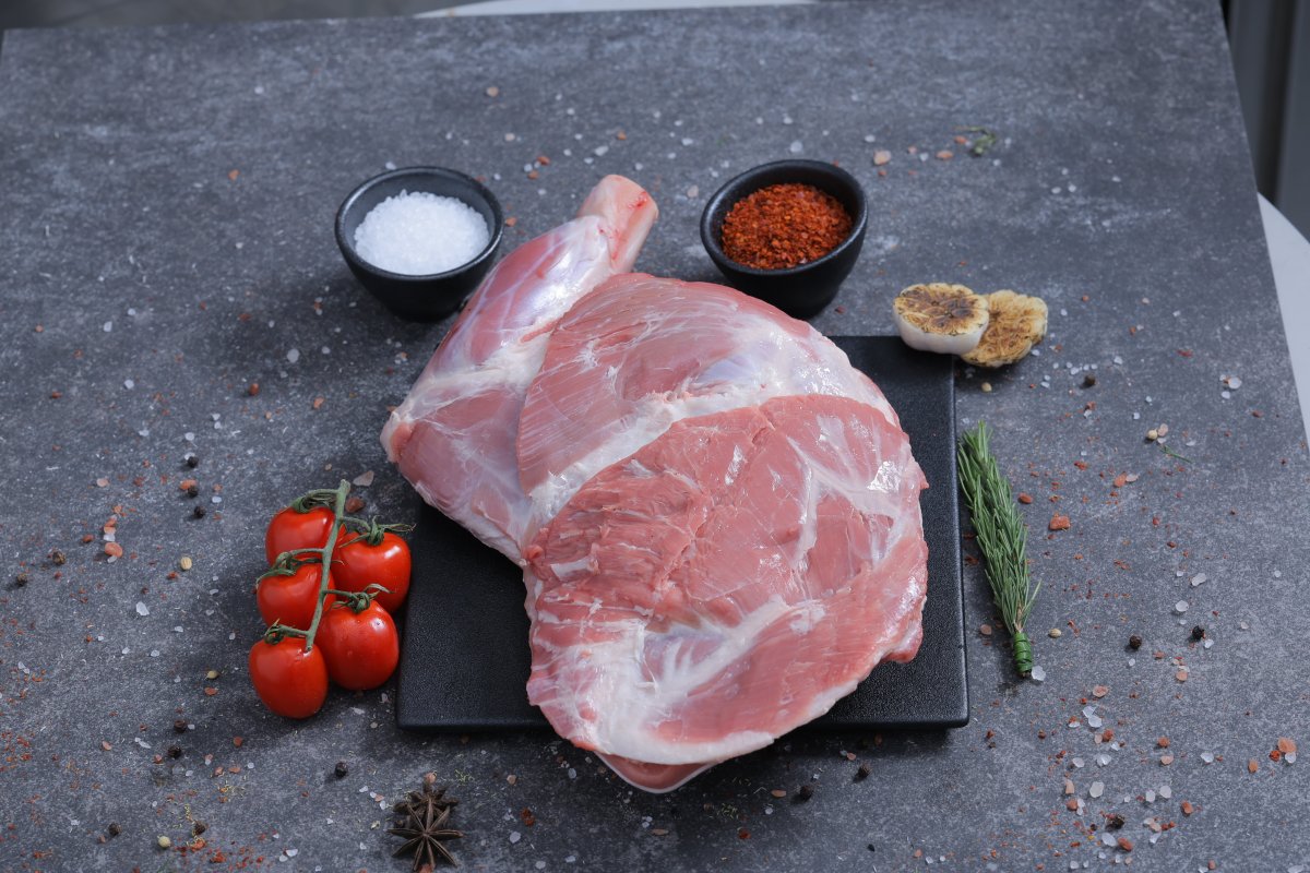 Whole raw lamb shoulder joint on a slate board with sea salt and spices - The Meat Master Butchery