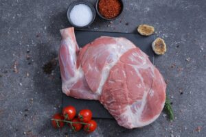 Two whole raw lamb legs on a slate board with salt and spices - fresh from The Meat Master Butchery