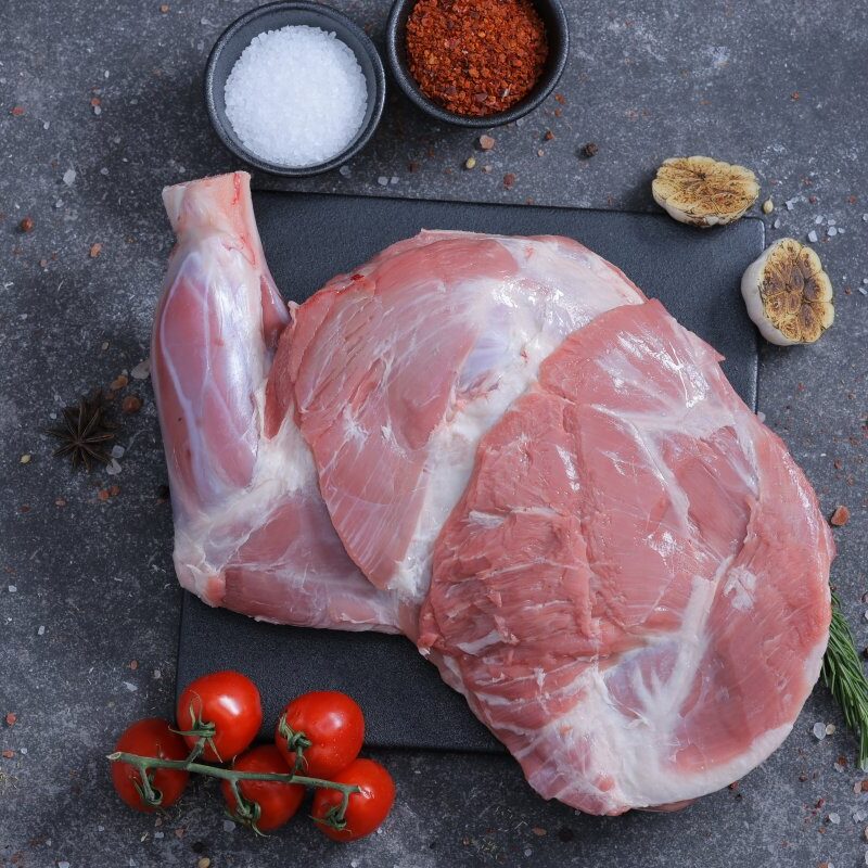 Two whole raw lamb legs on a slate board with salt and spices - fresh from The Meat Master Butchery