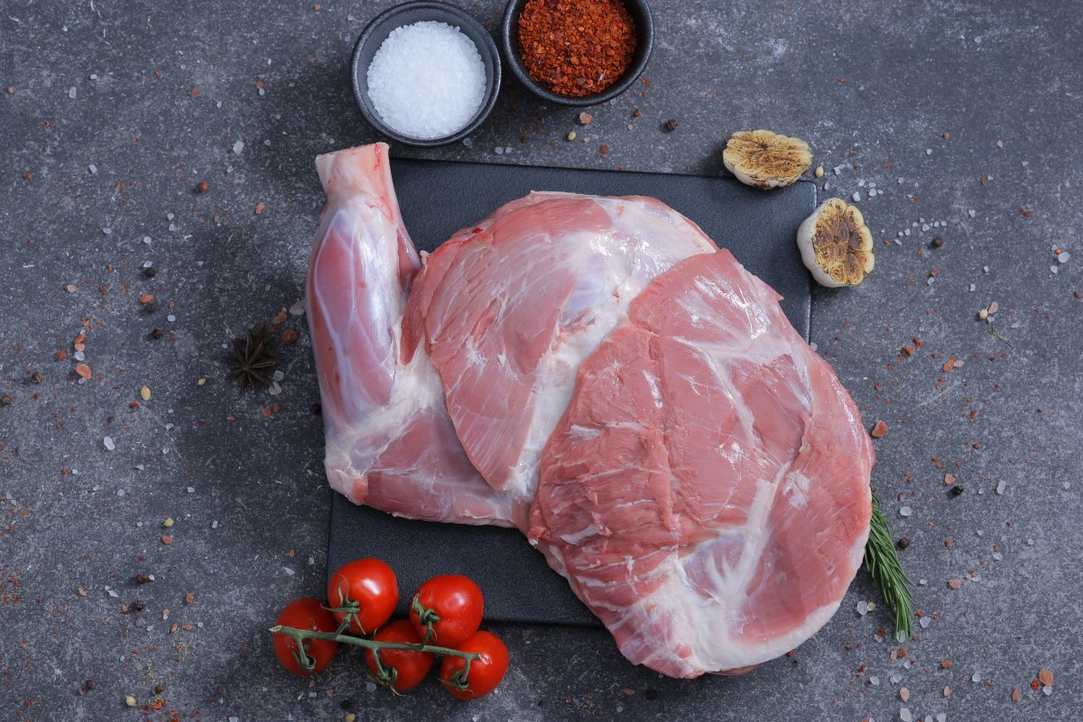 Two whole raw lamb legs on a slate board with salt and spices - fresh from The Meat Master Butchery