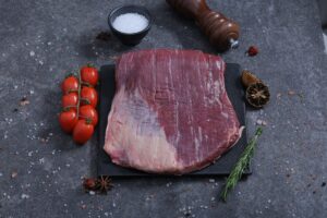 Large raw beef flank steak on a slate board with sea salt and rosemary - The Meat Master Butchery