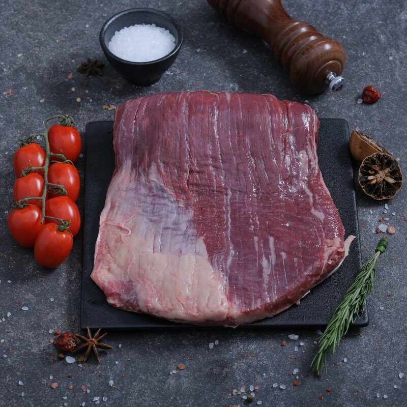 Large raw beef flank steak on a slate board with sea salt and rosemary - The Meat Master Butchery