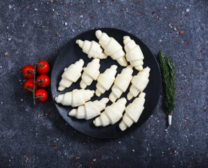 Raw unbaked mini croissants arranged on a black plate - fresh bakery at The Meat Master Butchery