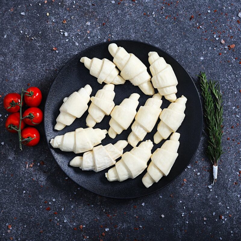Raw unbaked mini croissants arranged on a black plate - fresh bakery at The Meat Master Butchery