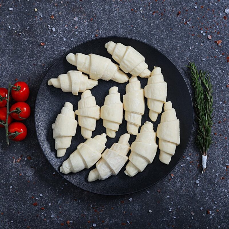 Mini raw croissants ready to bake on a black plate different angle - fresh bakery at The Meat Master Butchery