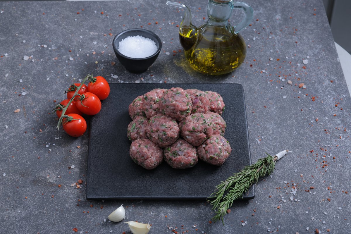 Raw herb-spiced minced meat balls on a slate board with olive oil - fresh from The Meat Master Butchery