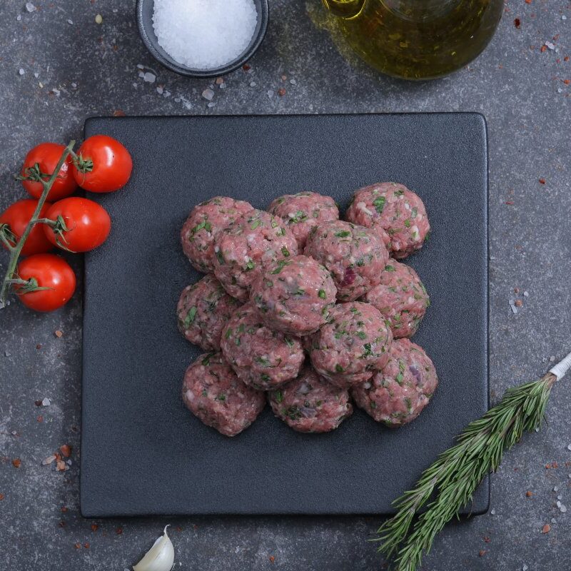 Raw herbed meatballs on a slate board with cherry tomatoes - fresh from The Meat Master Butchery