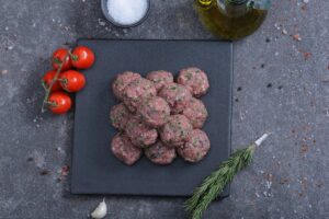 Raw spiced meat balls overhead shot on a slate board - fresh from The Meat Master Butchery